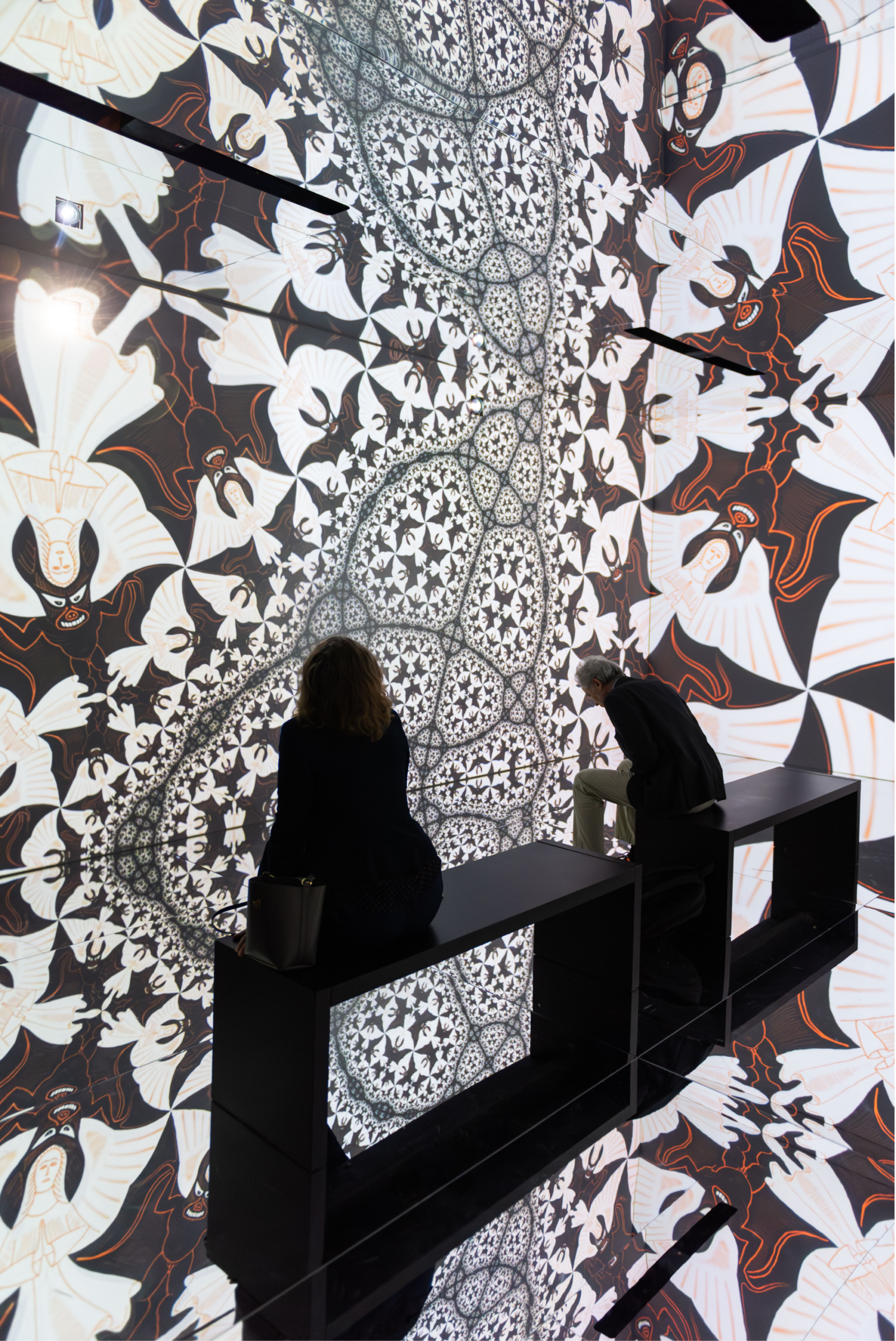 Black and white Escher tessellation projected across walls and floor