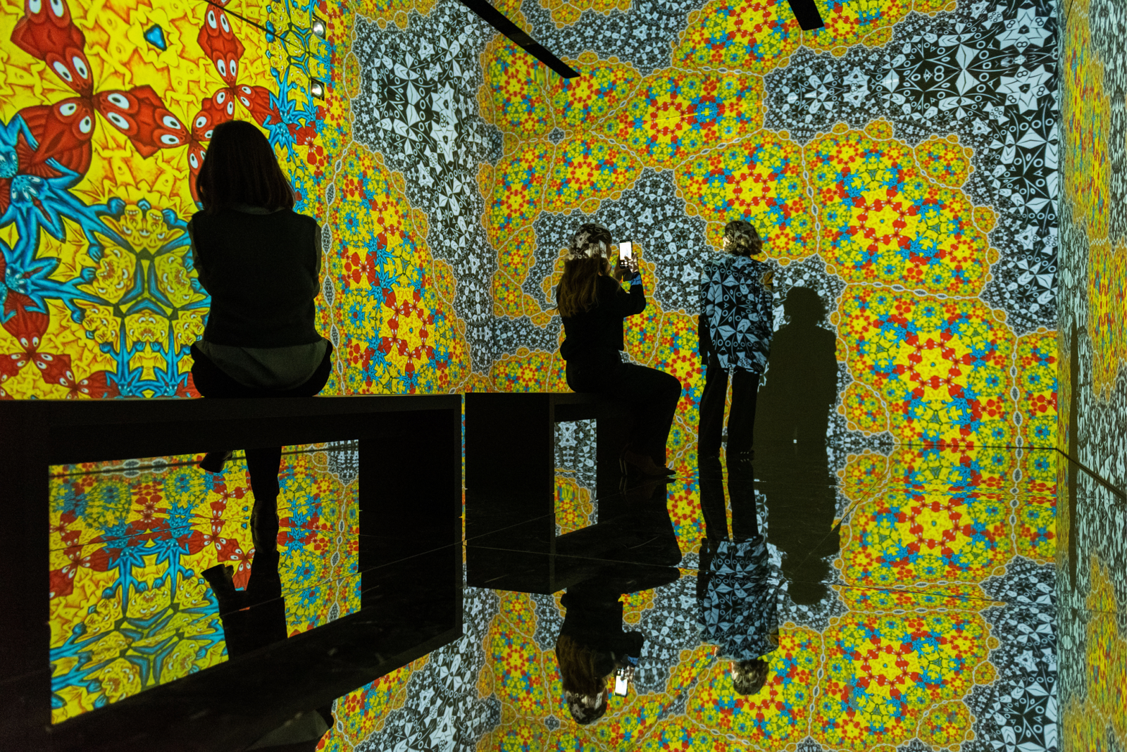 Visitors inside the infinity room, surrounded by a projected Escher tessellation